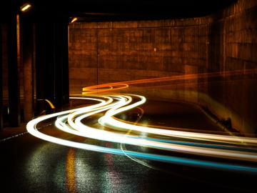 photographic long exposure of cars traveling thru a tunnel.