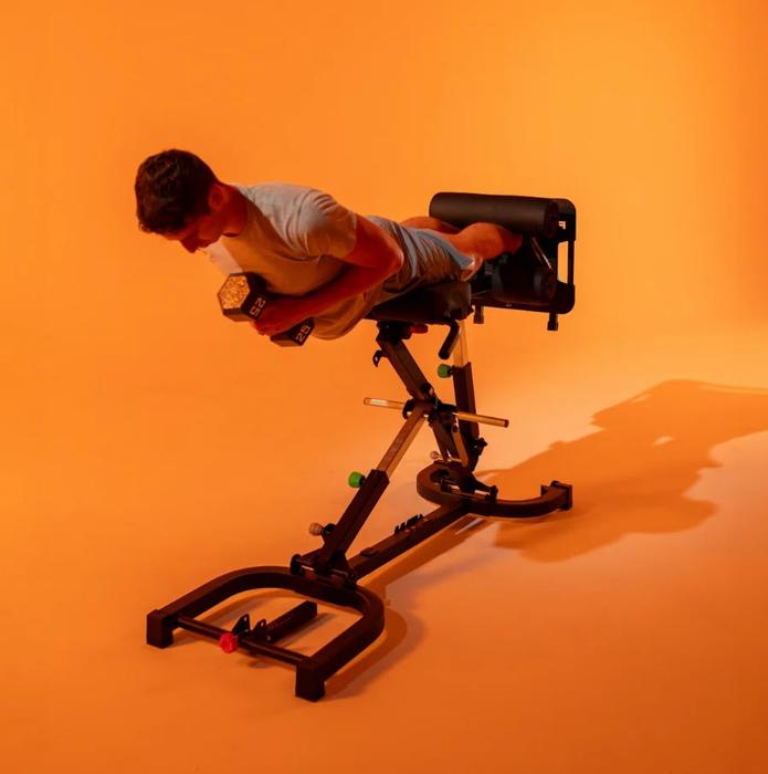 A motivated female athlete in activewear performing a walking lunge in a gritty, industrial-style gym. The atmosphere conveys determination and strength, emphasized by the 'FREAK ATHLETE' logo overlay in bold orange, suggesting a brand that champions intense workouts and formidable athletic performance.